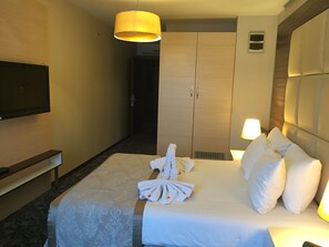 A hotel room with a bed, a flat-screen TV mounted on the wall, a bedside table, a lamp, and a wardrobe. - Derpa Suite Hotel Osmanbey (Istanbul)