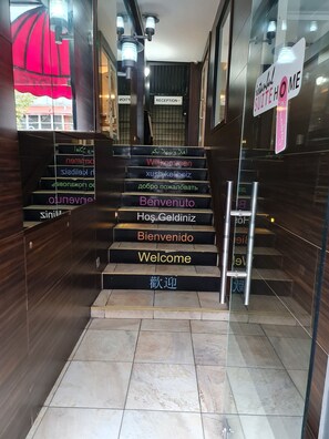 A staircase with multilingual welcome signs leading to a reception area. - Derpa Suite Hotel Osmanbey (Istanbul)