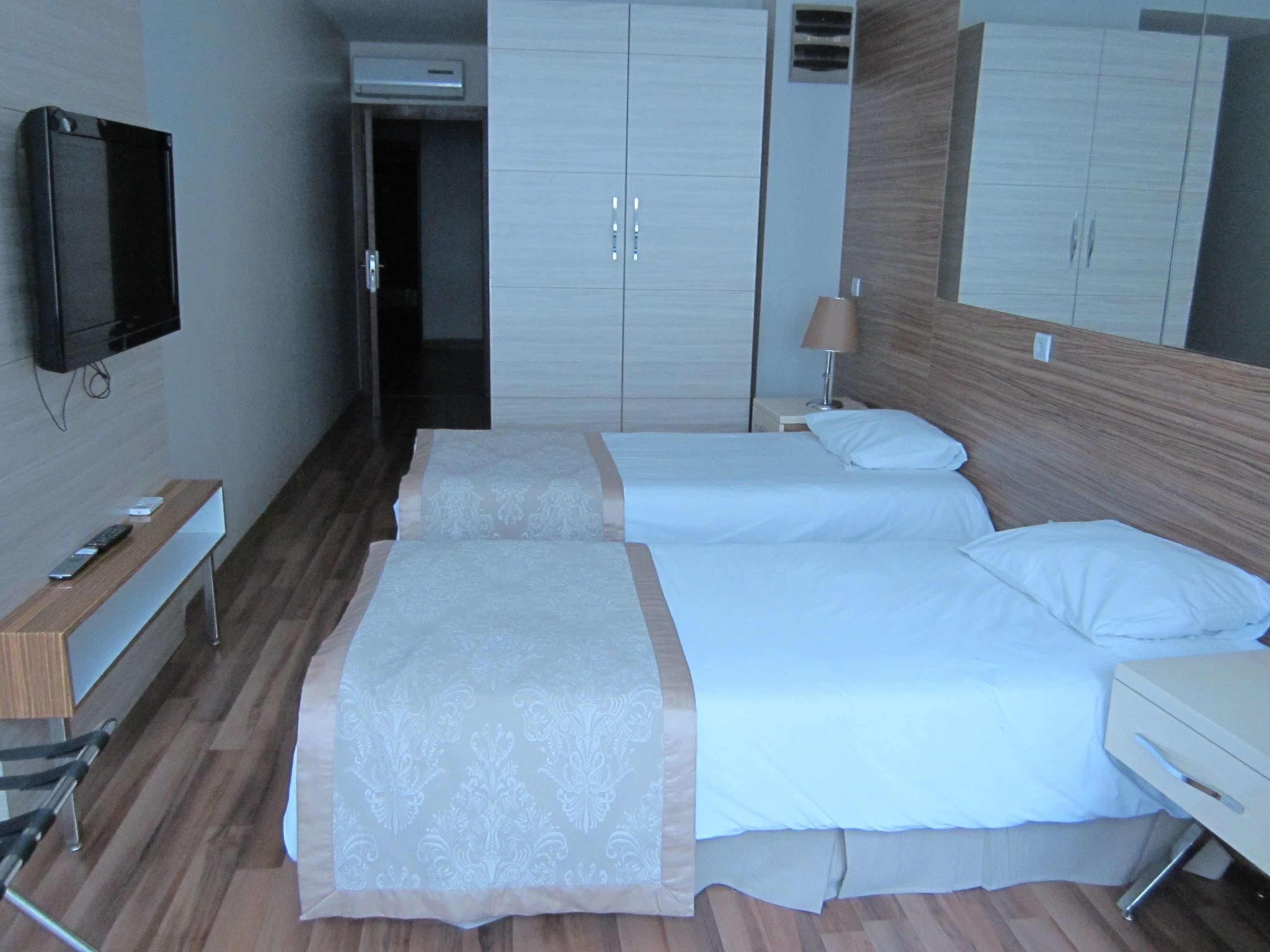 A hotel room with two beds, a TV, a desk, and a wardrobe.