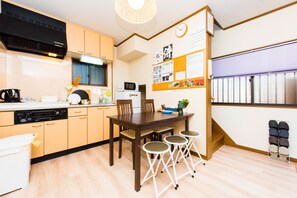 Una cocina compacta con armarios de madera, un microondas y un comedor con una mesa y cuatro sillas.