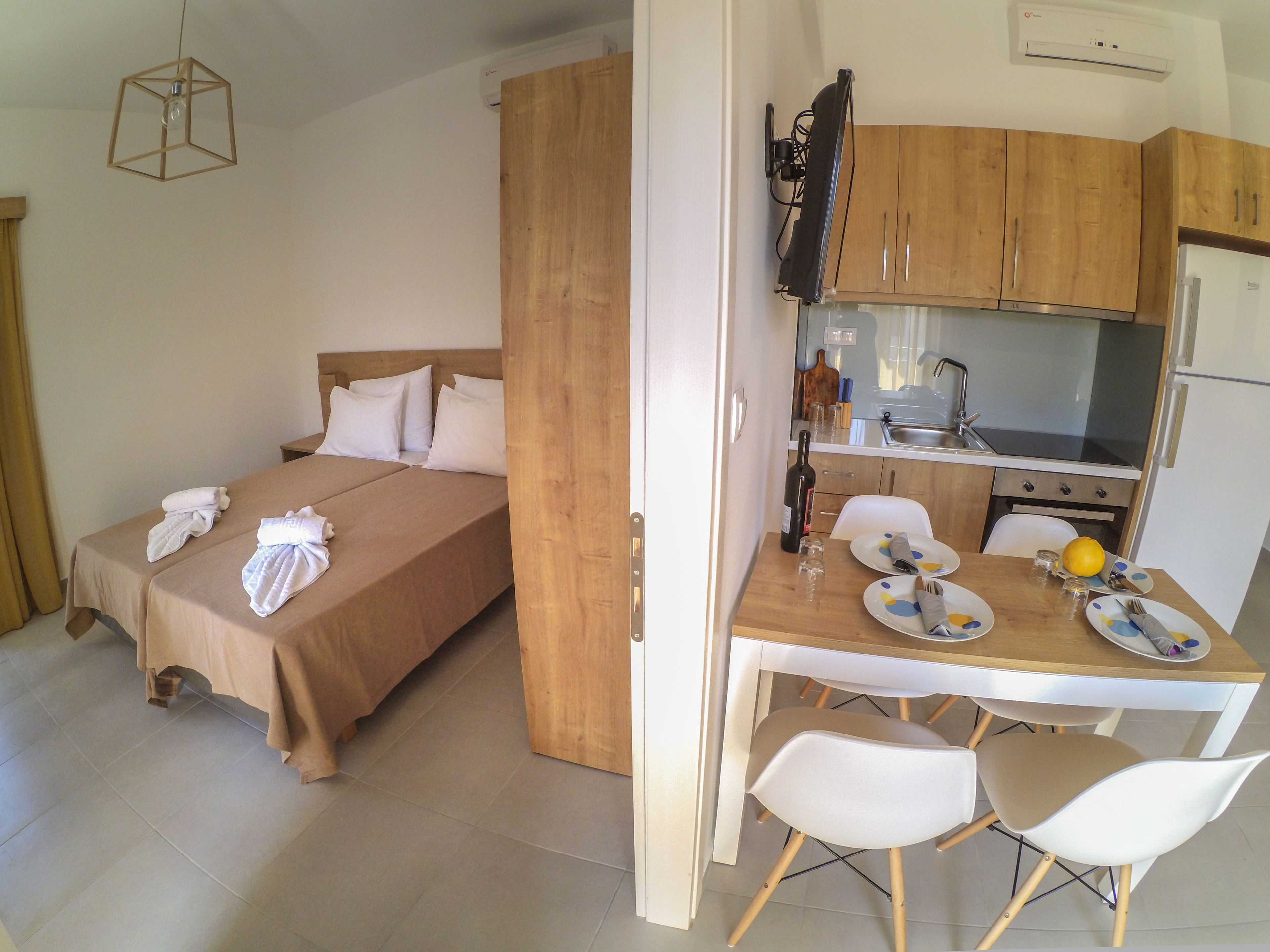 A compact room with a bed, a small kitchenette, and a dining area.