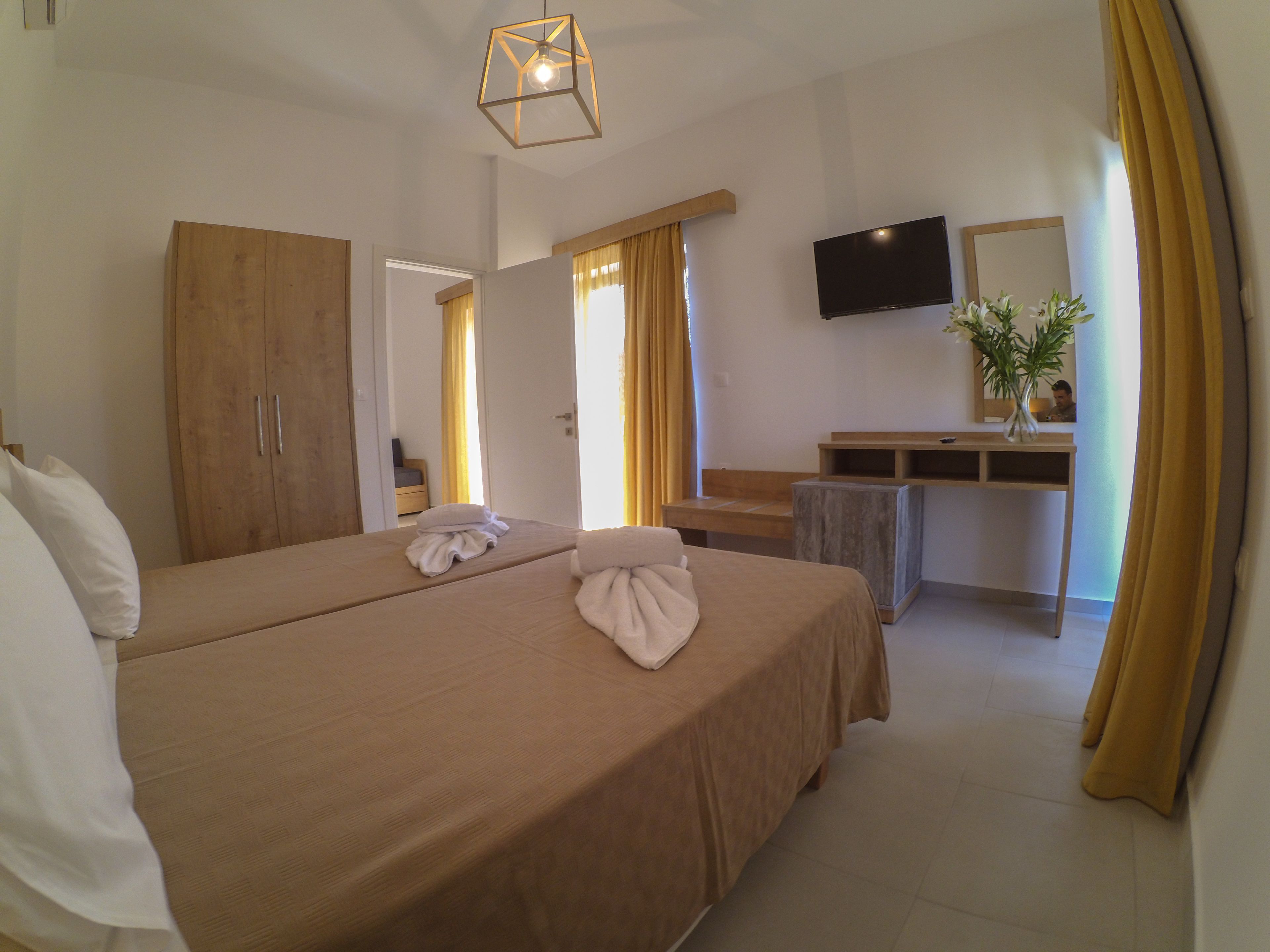 A hotel room with a large bed, a desk, a TV, and a bathroom visible through an open door.