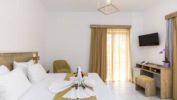 Una habitación de hotel con una cama bien hecha, un cabecero de madera, un escritorio con una computadora, un televisor y una ventana con cortinas.