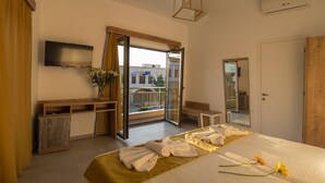 A hotel room with a bed, a TV, a balcony, and a view of the city. - Castell hotel (Kissamos)