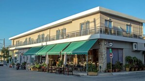 A two-story building with a green awning, outdoor seating, and a balcony. - Castell hotel (Kissamos)