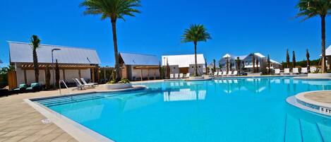 A swimming pool with lounge chairs and palm trees.