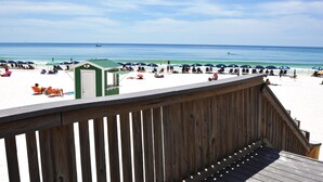 A beach with a wooden deck overlooking the sand and ocean.