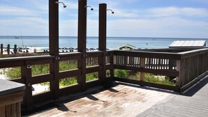 A wooden deck with a view of the beach and ocean.