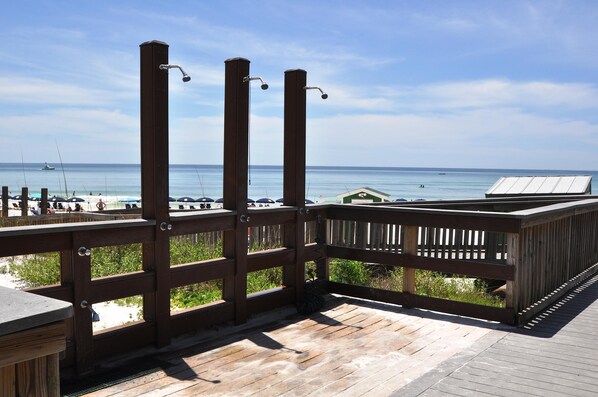 A wooden deck with a view of the beach and ocean.