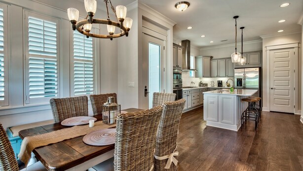 A spacious kitchen with modern appliances, a dining area with wicker chairs, and a chandelier. - Coasting Inn 3 Bedroom Condo By Coastal Dreamin (Santa Rosa Beach)