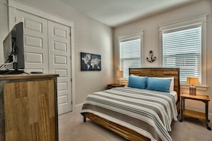 A bedroom with a bed, a desk with a computer, a world map on the wall, and two windows with blinds. - Coasting Inn 3 Bedroom Condo By Coastal Dreamin (Santa Rosa Beach)