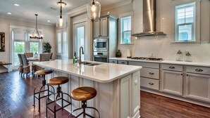 A modern kitchen with a large island, stainless steel appliances, and pendant lighting. - Coasting Inn 3 Bedroom Condo By Coastal Dreamin (Santa Rosa Beach)