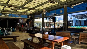 An indoor dining area with wooden tables and benches, large windows, and ceiling fans. - Coasting Inn 3 Bedroom Condo By Coastal Dreamin (Santa Rosa Beach)