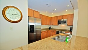 A kitchen with wooden cabinets, stainless steel appliances, and a granite countertop. - Redfish Village M2 214 3 Bedroom Condo By Coastal Dreamin (Santa Rosa Beach)