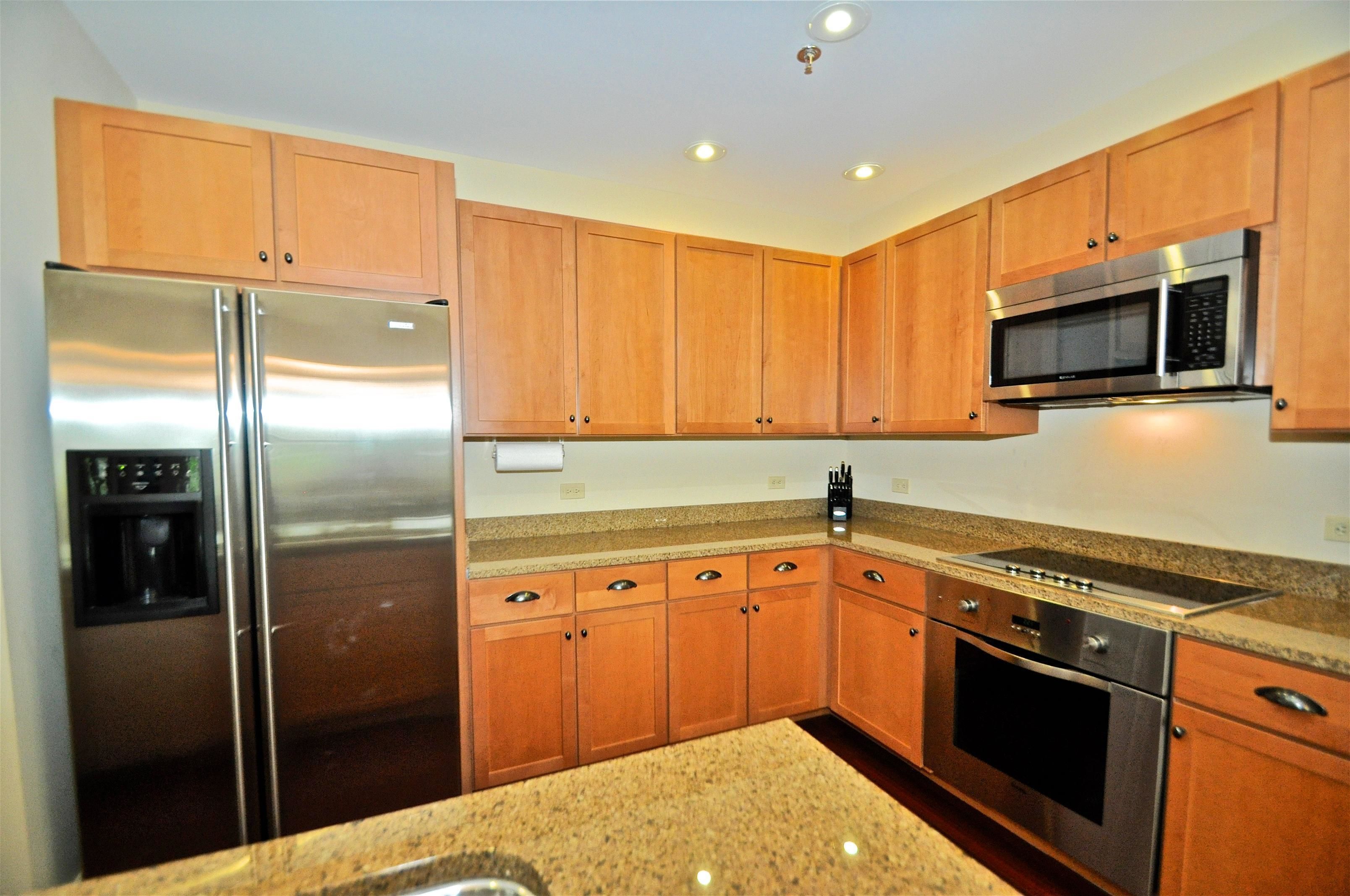 A kitchen with wooden cabinets, stainless steel appliances, granite countertops, and a built-in oven.