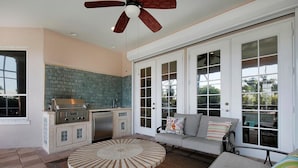 A patio area with a round table, a built-in grill, and a sofa with cushions. - BRF335 3 Bedroom Holiday Home by Marco Naples Vacation Homes (Marco Island)