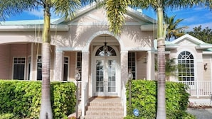A two-story house with a symmetrical facade, a central entrance with a decorative arch, and a covered porch area. - BRF335 3 Bedroom Holiday Home by Marco Naples Vacation Homes (Marco Island)