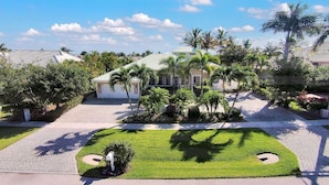 A residential area with a well-maintained lawn, palm trees, and a house with a sloped roof. - BRF335 3 Bedroom Holiday Home by Marco Naples Vacation Homes (Marco Island)