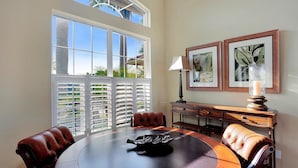 A dining area with a round table, leather chairs, a lamp, and framed botanical prints on the wall. - COPPER20 5 Bedroom Holiday Home by Marco Naples Vacation Homes (Marco Island)