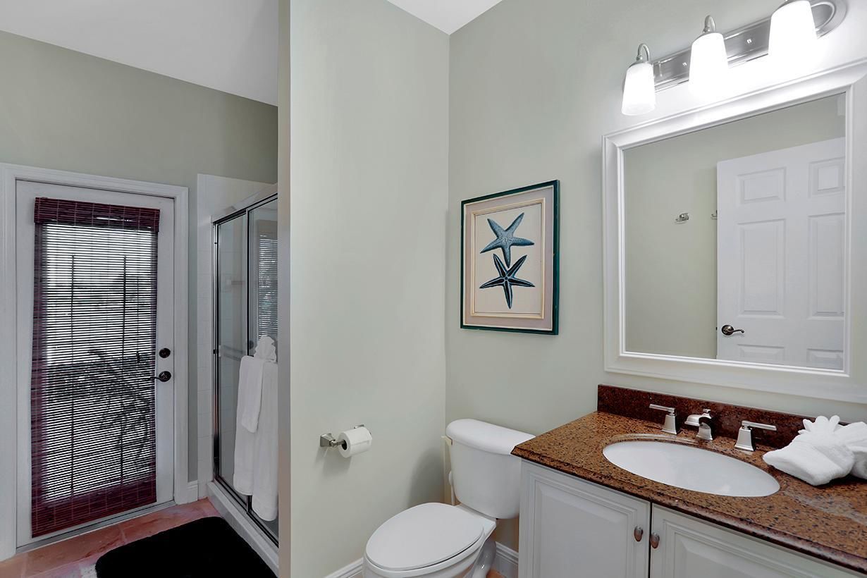 A bathroom with a shower, toilet, sink, and a large mirror.