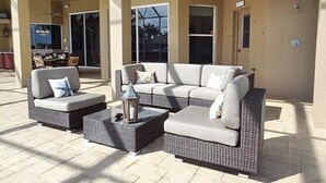 Un área de patio exterior con un sofá modular, dos sillones y una pequeña mesa.