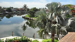 Una vista tranquila frente al agua, con un lago sereno, palmeras y un muelle que se adentra en el agua.