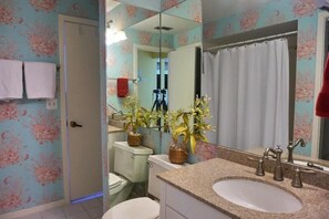 A bathroom with a floral wallpaper, a sink with a mirror, and two potted plants. - KEN407 5 Bedroom Holiday Home by Marco Naples Vacation Homes (Marco Island)