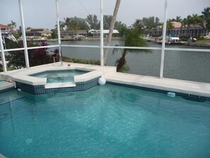 A swimming pool with a hot tub area, surrounded by a view of a marina and palm trees. - KEN486 3 Bedroom Holiday Home by Marco Naples Vacation Homes (Marco Island)