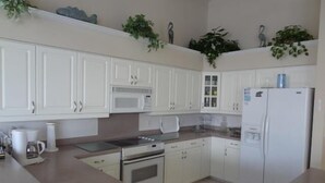 A kitchen with white cabinets, a microwave, a stove, a refrigerator, and a sink. - KEN486 3 Bedroom Holiday Home by Marco Naples Vacation Homes (Marco Island)