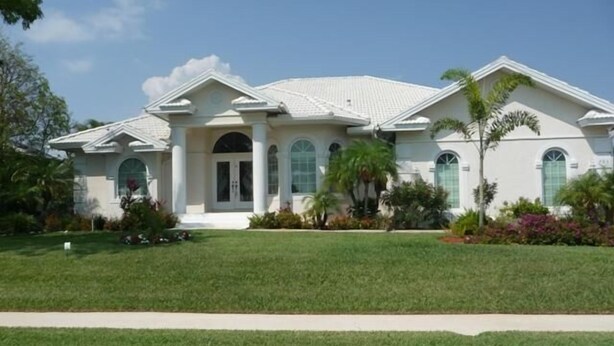 A large, single-story building with a symmetrical facade, featuring a central entrance flanked by columns, arched windows, and a triangular pediment. - KEN486 3 Bedroom Holiday Home by Marco Naples Vacation Homes (Marco Island)
