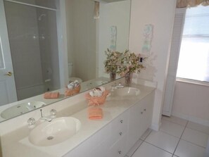 A bathroom with a double sink, a large mirror, and a vase with flowers on the vanity. - KEN486 3 Bedroom Holiday Home by Marco Naples Vacation Homes (Marco Island)