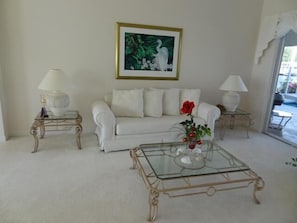 A living room with a white sofa, two glass coffee tables, and a framed painting on the wall. - KEN486 3 Bedroom Holiday Home by Marco Naples Vacation Homes (Marco Island)