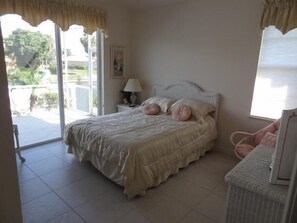 A bedroom with a bed, a nightstand, a lamp, and a view of the outdoors. - KEN486 3 Bedroom Holiday Home by Marco Naples Vacation Homes (Marco Island)