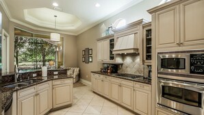 A spacious kitchen with granite countertops, stainless steel appliances, and beige cabinetry. - MAJ8978 4 Bedroom Holiday Home by Marco Naples Vacation Homes (Naples)