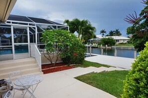 Ein überdachter Außenbereich mit Pool, einer Glasumrandung und einer kleinen Terrasse mit Tisch und Stühlen.