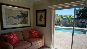 A living room with a brown sofa, two red pillows, and two framed artworks on the wall.