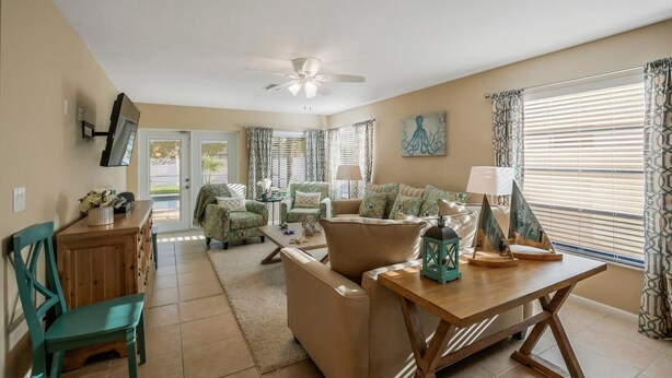 A living room with a sofa set, a wooden coffee table, and a television mounted on the wall.