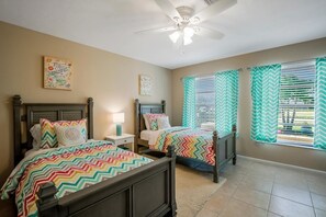 A bedroom with two beds, a ceiling fan, and chevron-patterned curtains. - NP97th 689 3 Bedroom Holiday Home by Marco Naples Vacation Homes (Naples)