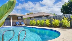 A swimming pool with metal ladders, surrounded by a wooden fence and small plants. - NP97TH 730 3 Bedroom Holiday Home by Marco Naples Vacation Homes (Naples)