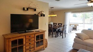 A living room with a TV, wooden cabinet, dining table, and chairs. - NP97TH 730 3 Bedroom Holiday Home by Marco Naples Vacation Homes (Naples)