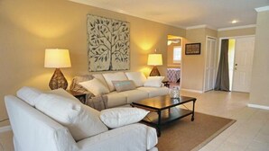 A living room with a beige sofa set, two lamps, a coffee table, and a decorative wall piece. - NP97TH 730 3 Bedroom Holiday Home by Marco Naples Vacation Homes (Naples)