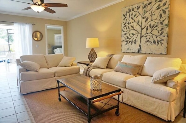 A living room with two beige sofas, a wooden coffee table, and a floor lamp.