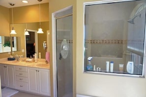 A bathroom with two sinks, a shower, and a window with toiletries. - SHEF2024 4 Bedroom Holiday Home by Marco Naples Vacation Homes (Marco Island)