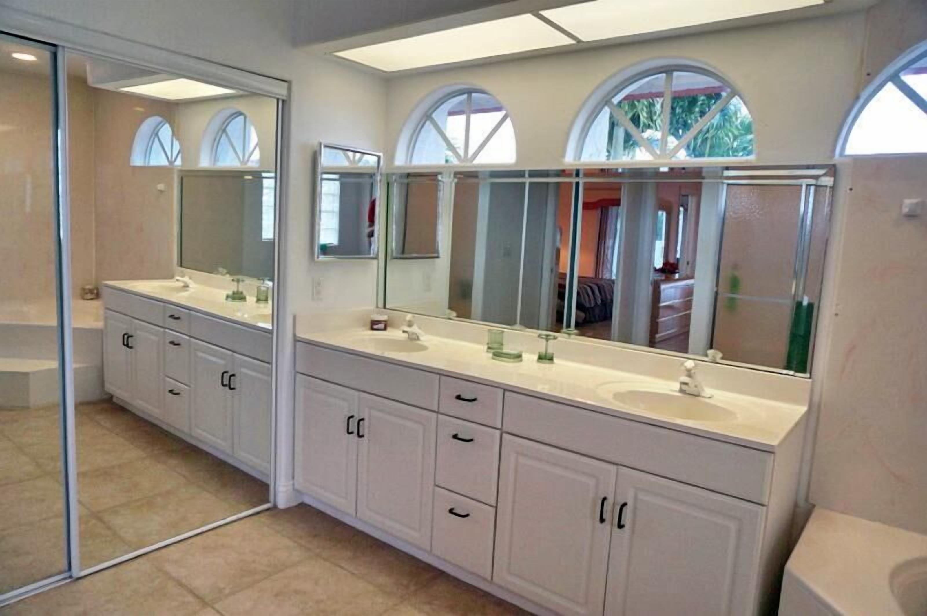 A bathroom with two sinks, large mirrors, and a glass shower enclosure.