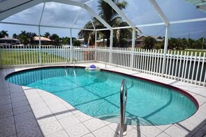 A swimming pool with a white fence, a pool ladder, and a clear blue water surface. - SHEN1124 3 Bedroom Holiday Home by Marco Naples Vacation Homes (Marco Island)