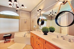 A modern bathroom with a double sink vanity, a large mirror, and a bathtub. - SMARCO1601 4 Bedroom Holiday Home by Marco Naples Vacation Homes (Marco Island)