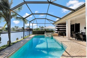 A swimming pool with a view of a body of water, a covered patio area, and outdoor furniture. - SMARCO1601 4 Bedroom Holiday Home by Marco Naples Vacation Homes (Marco Island)
