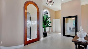 A spacious hallway with a large mirror, a potted plant, and a decorative table.