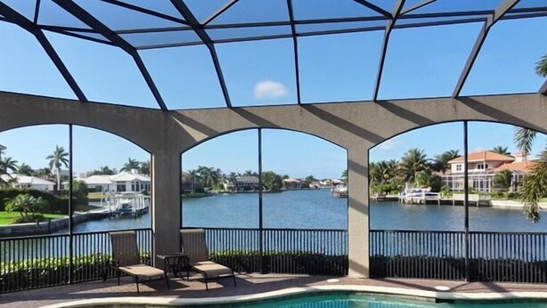 A pool area with a view of a lake and surrounding houses.