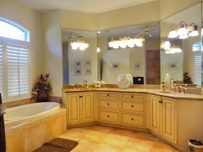 A bathroom with a large vanity, a bathtub, and a large mirror.